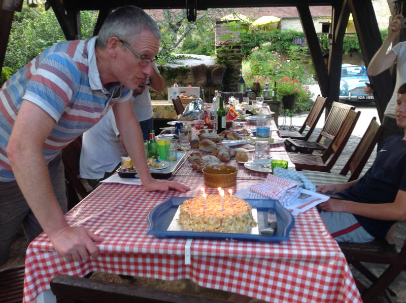 homme soufflant les bougie sur son gâteau d'anniversaire
